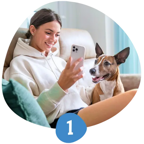 Happy DuraPaw customer relaxing on the couch, showing her excited dog the subscription box on her phone